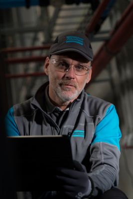 Male service technician in a working environment holding a tablet or pc