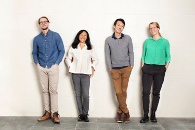 Colleagues in the office leaning against a wall. 