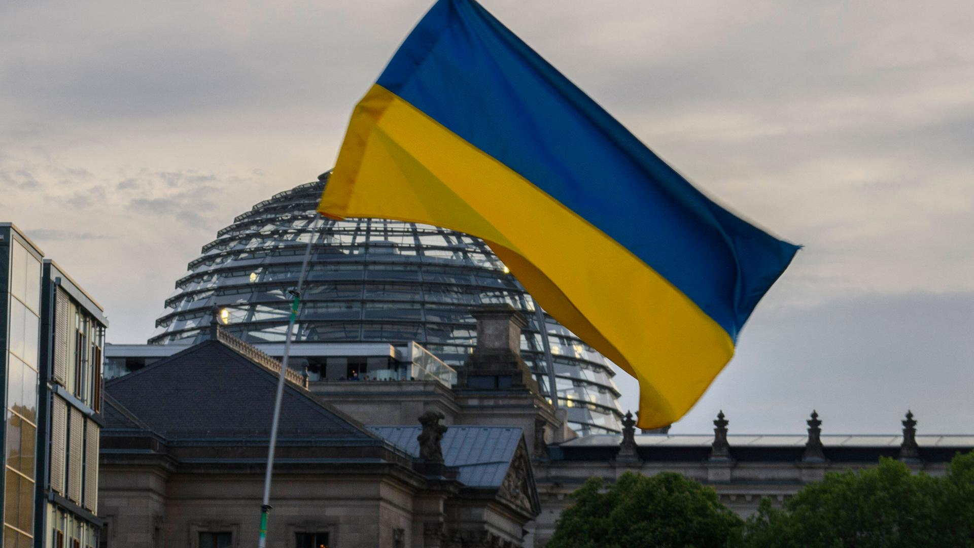 Eine Ukraine-Flagge weht bei einer Demonstration gegen den russischen Angriffskrieg vor dem Bundestag in Berlin (Archivbild)