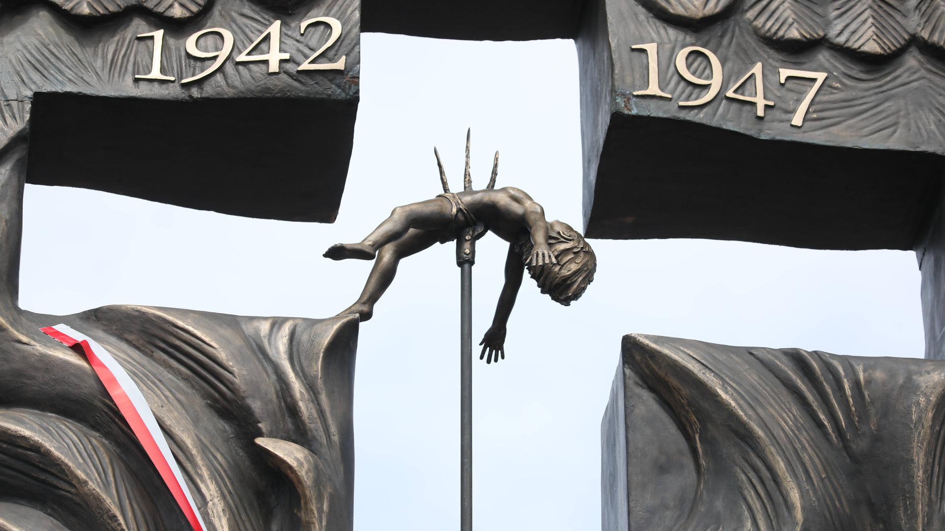 Eine Bronzeskultur zeigt ein auf einem Dreizack aufgespiesstes Kind in einem Kreuz.