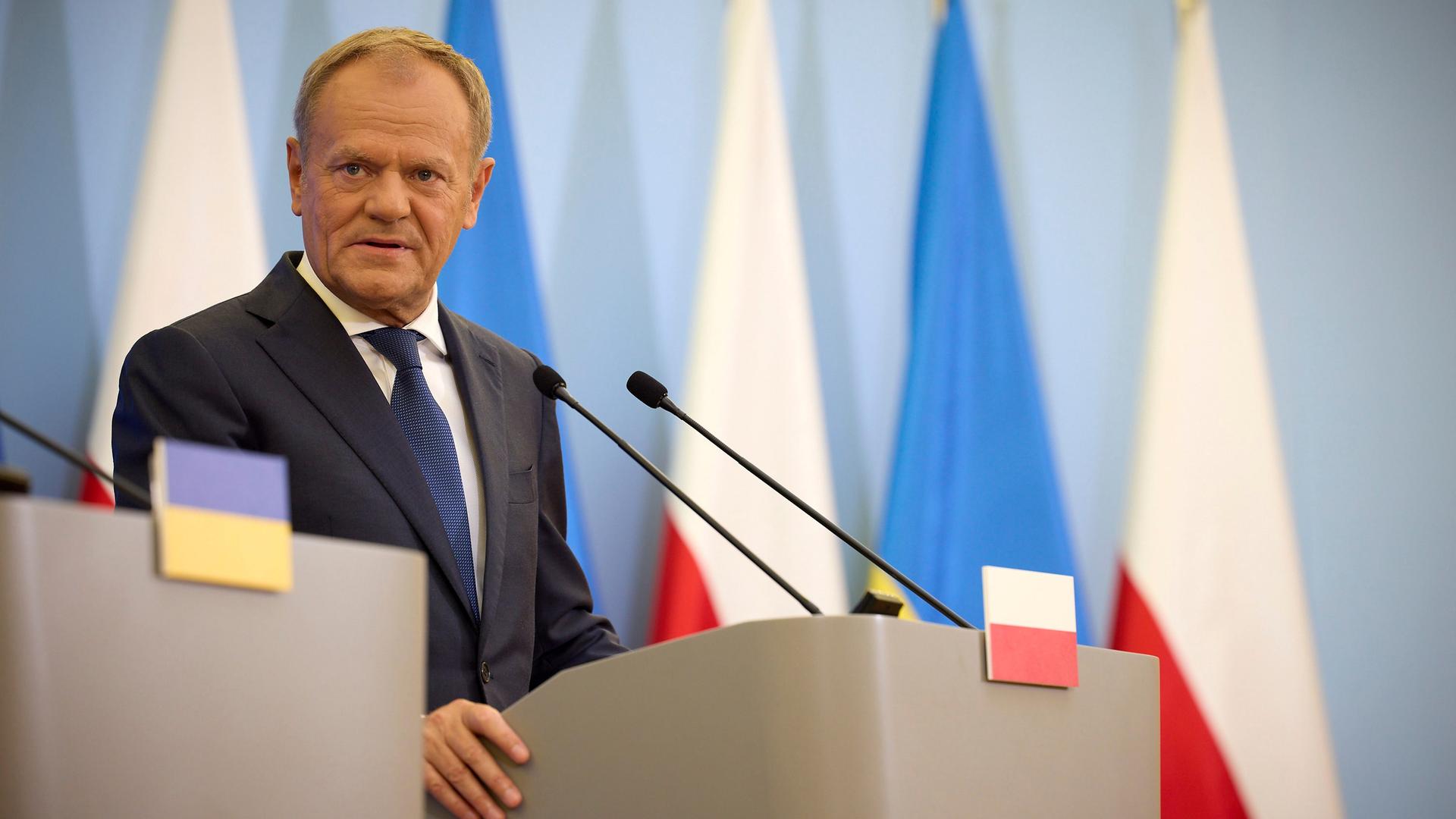 Ein Mann steht an einem Redepult und beantwortet Fragen. Er trägt einen Anzug. Es ist der polnische Premierminister Donald Tusk.