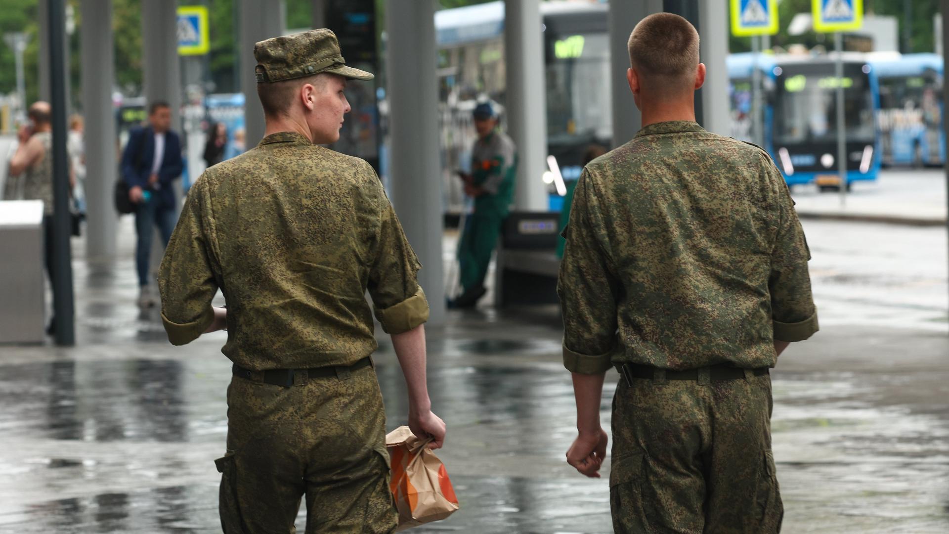 Zwei russische Soldaten schlendern über eine Straße in Moskau. Ansicht von hinten. 