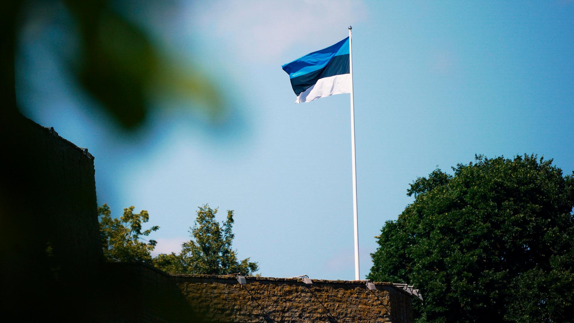 Auf der Burg Narwa in Estland weht eine estnische Flagge: drei gleich breite waagerechte Streifen in Blau, Schwarz und Weiß.