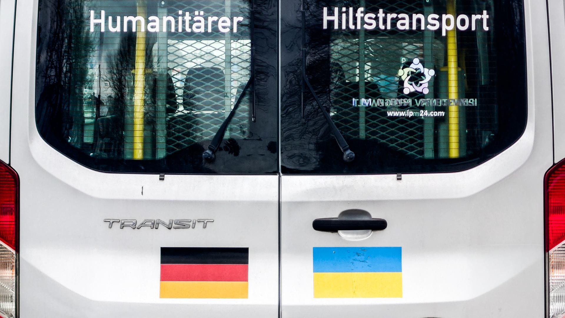 Die Rückseite eines Transporters für humanitäre Hilfe aus Deutschland, die für die Ukraine bestimmt ist. Auf die Tür des Fahrzeugs sind Aufkleber mit deutscher und ukrainischer Flagge und der Schriftzug "Humanitärer Hilfstransport".