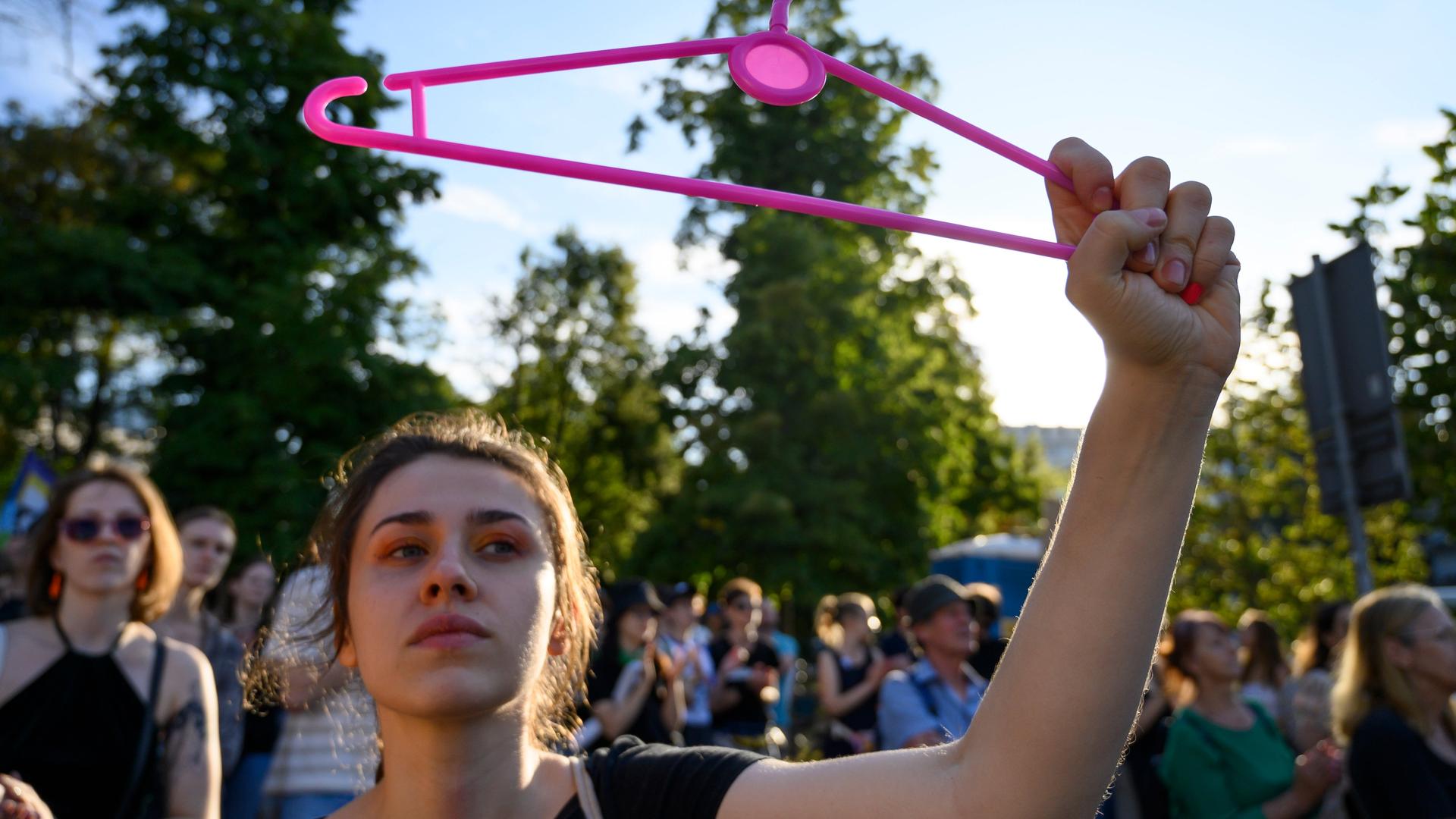 Eine Frau hält bei einer Demonstration in Warschau einen pinken Bügel hoch. Er steht für das Recht auf Abtreibung.