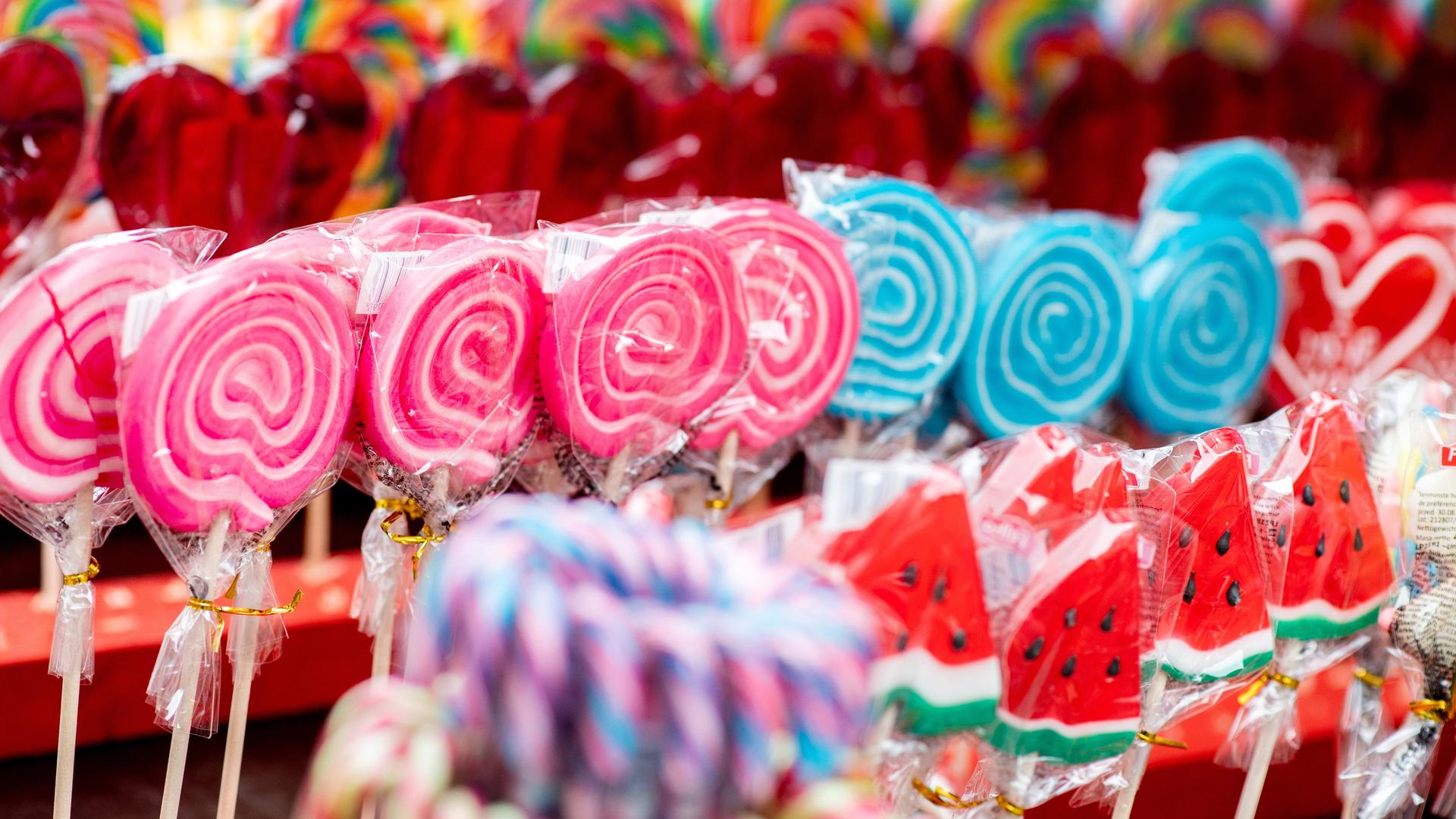 Bunte Lutscher werden während eines Volksfestes an einem Stand zum Kauf angeboten.