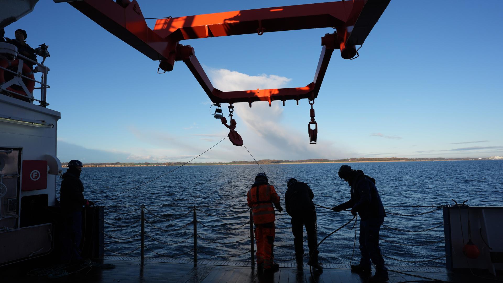 Besatzungsmitglieder ziehen in der Ostsee ein Kabel an Deck eines Forschungsschiffs. Mehr als fünf Jahre nach dem mysteriösen Verschwinden eines auf dem Grund fest verankerten Unterwasserobservatoriums gibt es neue Datensammler am Meeresgrund.