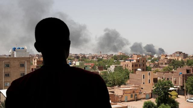 Rauch über Häusern in der sudanesischen Hauptstadt Khartum. Ein Mann steht im Vordergrund, er ist nur eine Silhouette.