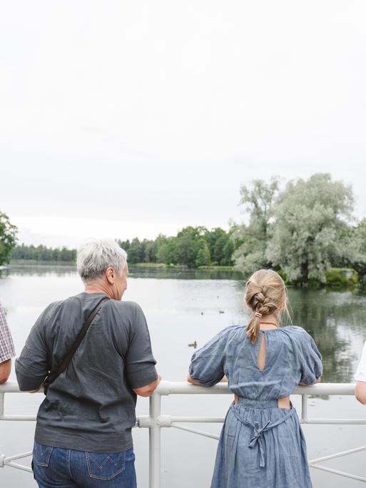 Ältere Frau und Mann gucken mit einem Mädchen und einem Jungen auf einen See.