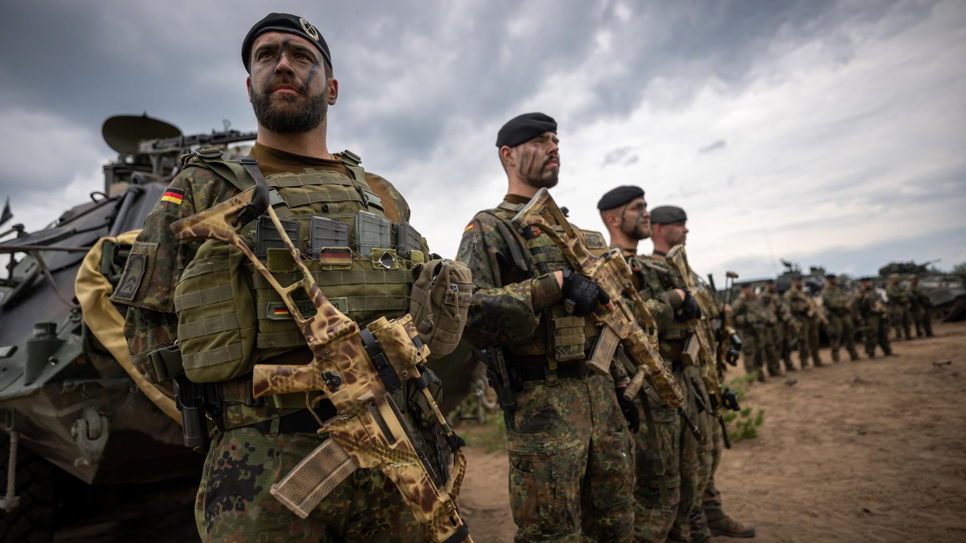 Soldaten der Bundeswehr in Uniform und mit Waffen in der Hand stehen beim Besuch von Kanzler Scholz im Camp Adrian Rohn. Bundeskanzler Scholz (SPD) hat Litauen zusätzliche militärische Unterstützung zugesagt.