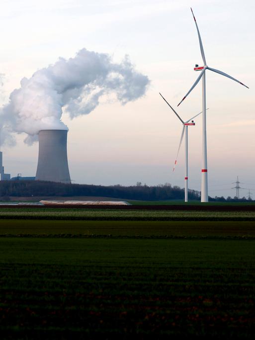 Strommasten und Windräder rund um das Kohlekraftwerk Neurath des Stromkonzerns RWE bei Grevenbroich. Aus den Kühltürmen steigen dicke Dampfwolken in den Himmel.  