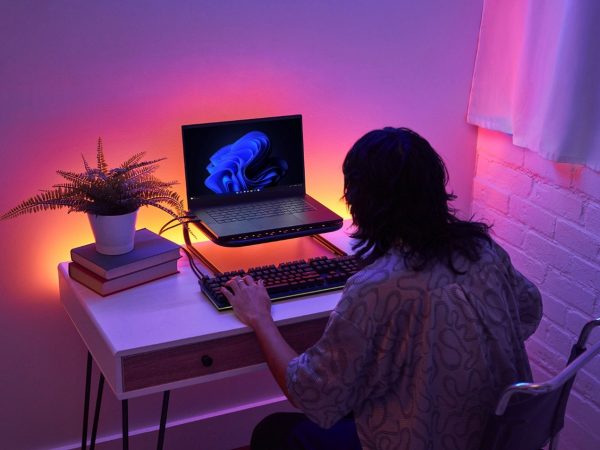 Person working at a laptop computer illuminated by colorful lighting