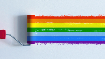 A paint roller painting a rainbow across a blank wall.