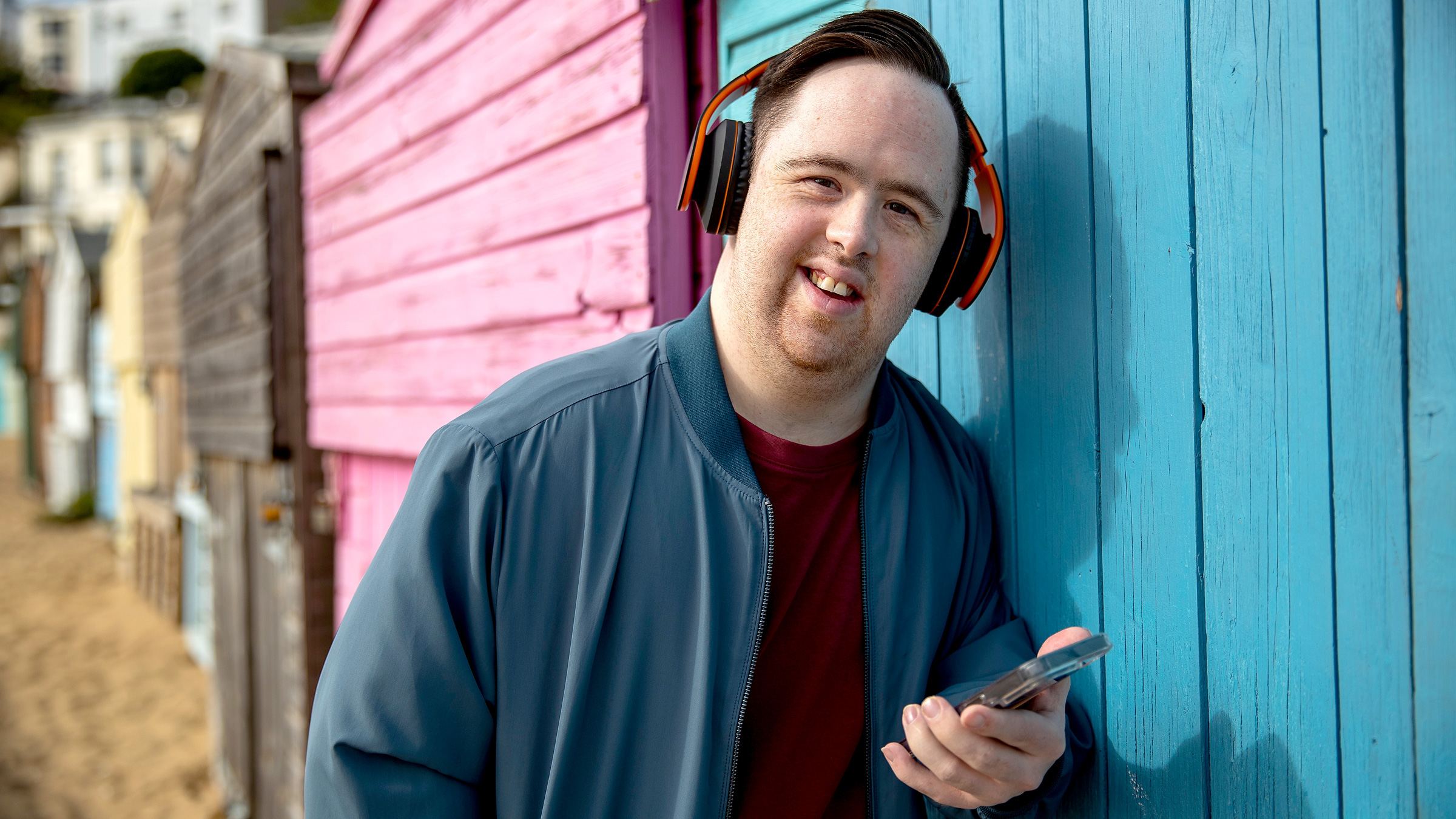 I/DD individual wearing headphones and holding a smartphone