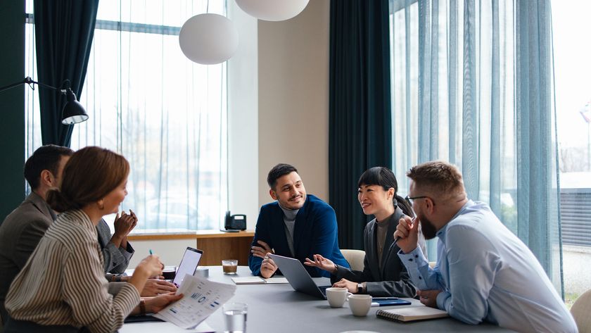 Executive leadership team concept image showing C-suite members, including CIO, CISO, CTO, and CEO, sitting around a table in an office.