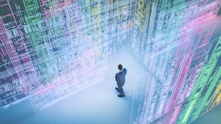 A businessman walking through a large virtual room filled with green, purple, and yellow screens showing abstract patterns to represent data ethics.