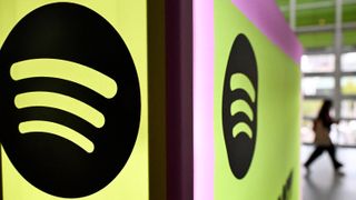 The Spotify logo on a display in an office building, shown on two different corners of a wall close to the camera. Decorative: the logo is set on a green background and a pink background.