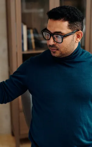 person with blue shirt and glasses using whiteboard 