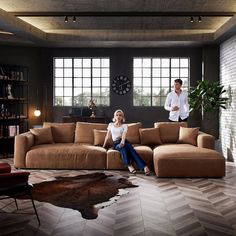 a man and woman sitting on top of a brown couch