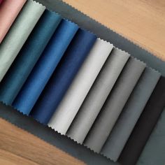 several different colors of fabric sitting on top of a wooden table next to each other