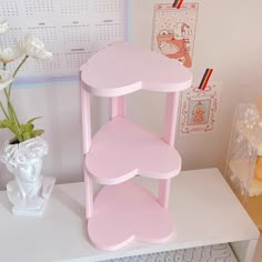 a pink shelf sitting on top of a desk next to a vase with white flowers