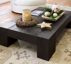 a coffee table with ornaments on it and a candle in the centerpiece, sitting on a rug