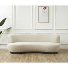 a white couch sitting on top of a hard wood floor next to a potted plant