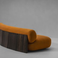 an orange couch sitting on top of a wooden table next to a gray wall and floor