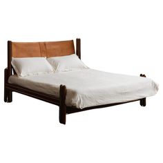 a bed with two pillows on top of it and a wooden frame around the headboard