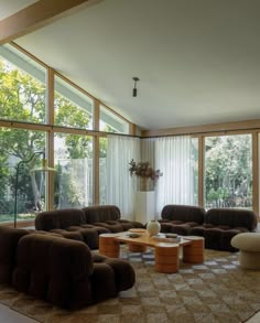 a living room filled with lots of furniture and large glass windows over the top of it