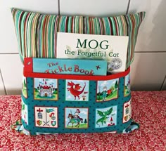 there is a pillow with pictures on it and a book in the back pocket that says mog, the forgetful cat