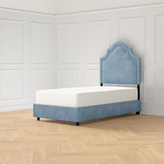 a bed sitting on top of a wooden floor next to a wall with white paneling