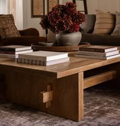 a coffee table with books on it and a vase full of flowers in the background