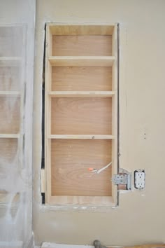 an empty shelf in the corner of a room with no one around it, and some tools on the floor