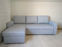 a gray couch sitting on top of a hard wood floor next to a white wall