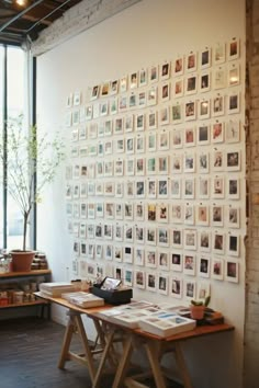 a wall with many pictures on it in an office space next to a desk and window