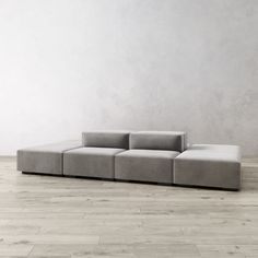 a gray couch sitting on top of a hard wood floor next to a white wall