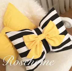 a yellow and black bow pillow sitting on top of a white chair