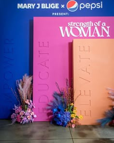 there are flowers sitting in front of the large sign that says strength of a woman