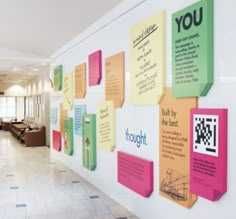 colorful sticky notes are on the wall in an office lobby with white tile flooring