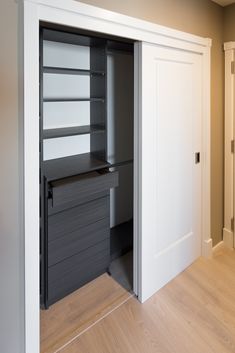 an empty closet with shelves and drawers on the door, in front of a white wall