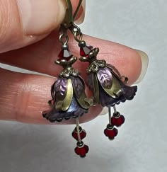 DARK FAIRY FLOWER EARRINGS  ▪️▪️▪️▪️▪️▪️▪️️▪️▪️▪️▪️▪️▪️ These pretty red purple floral earrings are made with super cute Lucite fairy flowers which have been hand painted with an iridescent finish. They have beautiful crystals added in eye catching deep Siam red for perfect sparkle when they move and are finished with antique bronze fish lever back earring hooks and ornate floral bead caps. They are very light weight and are perfect for special occasions, festivals and bridesmaids yet cute enoug Fairy Accessories Jewellery, Whimsigoth Earrings, Fae Jewelry, Whimsigoth Jewelry, Bronze Jewellery, Dark Accessories, Antique Bronze Jewelry, Whimsical Earrings, Fairy Flowers