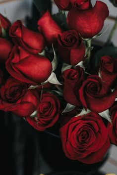 a vase filled with red roses on top of a table