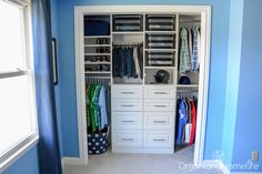 an organized closet with blue walls and white drawers