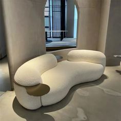 a white couch sitting on top of a floor next to a window