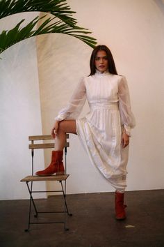 a woman is sitting on a chair and posing for the camera