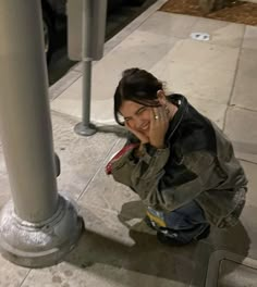 a woman sitting on the sidewalk talking on her cell phone