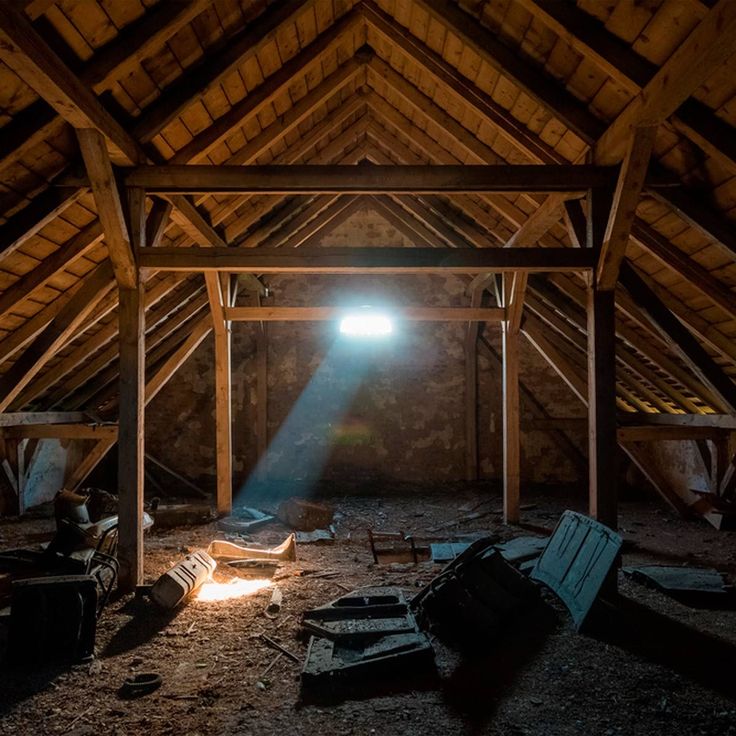 an attic with wood beams and light shining through the window on it's roof