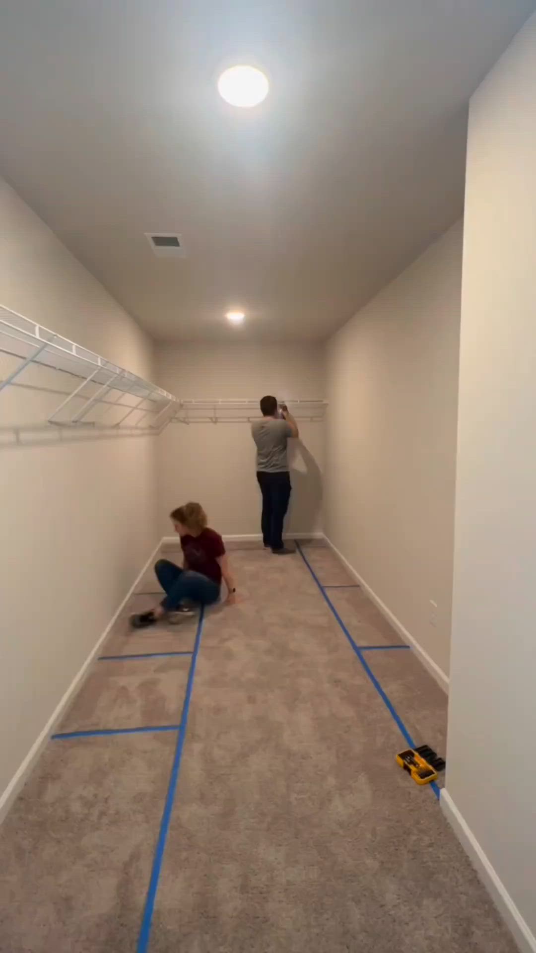 This may contain: two people are painting the walls in an empty room with blue tape on the floor