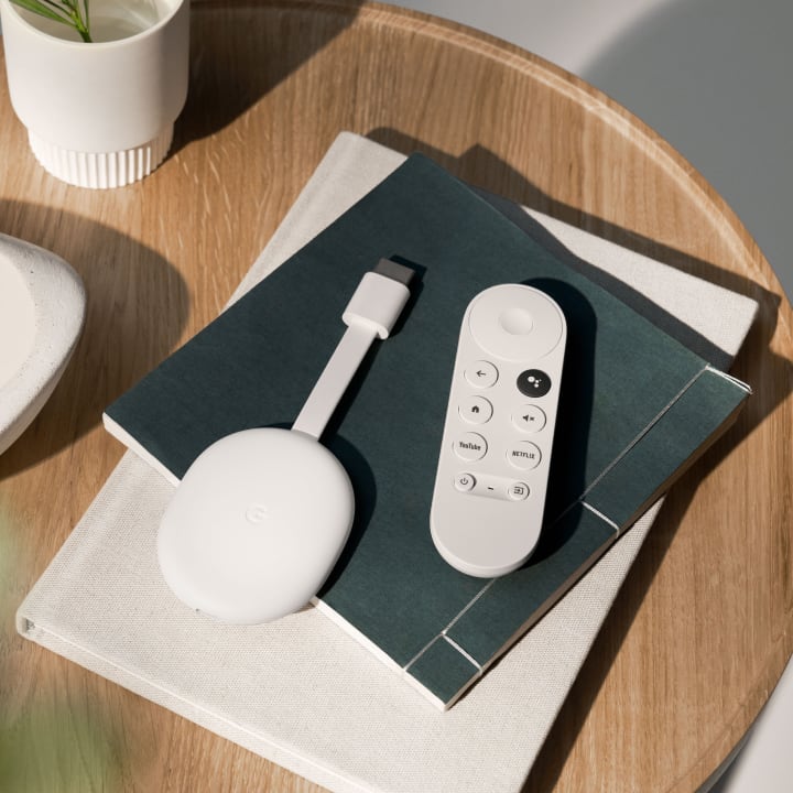 Chromecast with Google TV in Snow on a a pile of journals next to white ceramic pieces